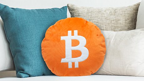 Das orange Bitcoin Kissen von ThinkItCrypto liegt als Krypto-Deko auf einem Sofa